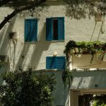 Sunny view of Mediterranean-style building with blue shutters in Budva, Montenegro.