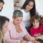 A family discusses real estate documents at home with a realtor, fostering communication and planning.