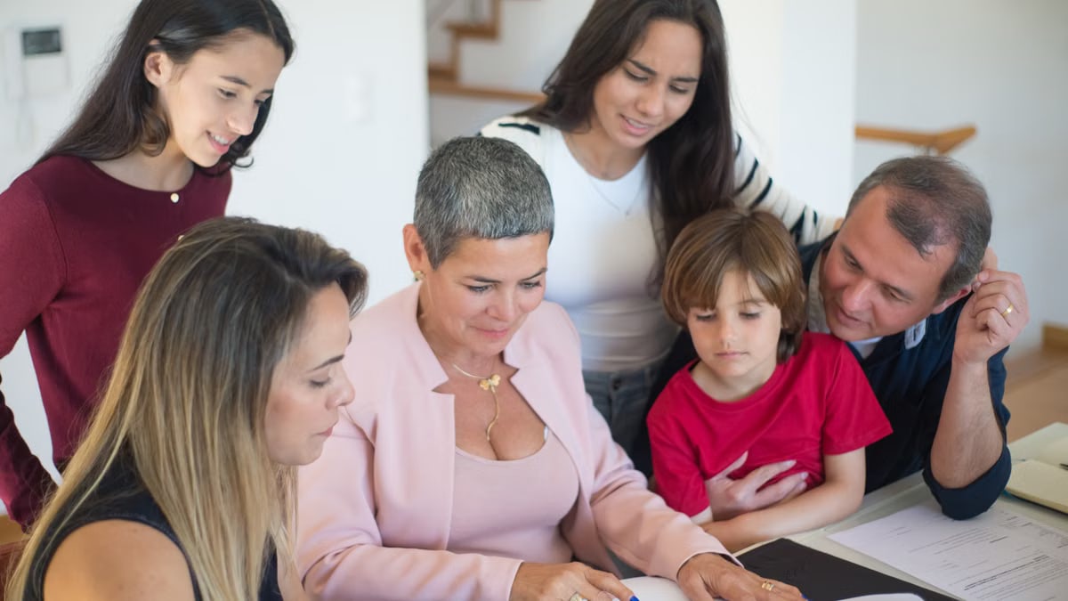 A family discusses real estate documents at home with a realtor, fostering communication and planning.