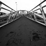 Black and white view of a city bridge with graffiti, highlighting geometric lines.