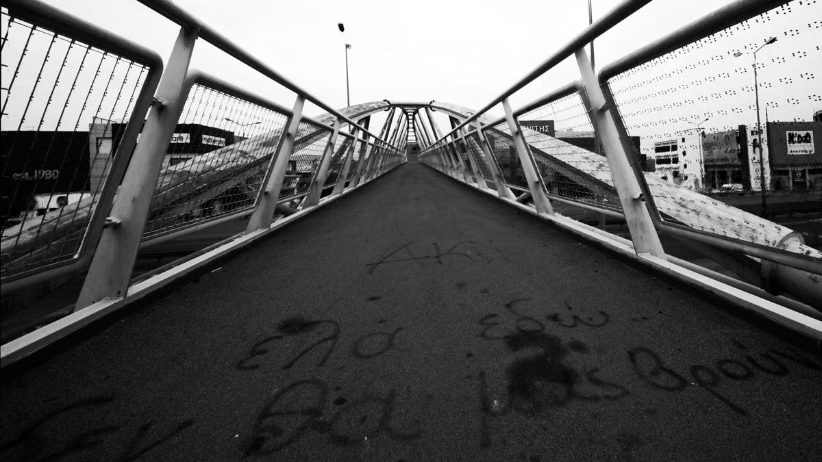 Black and white view of a city bridge with graffiti, highlighting geometric lines.